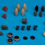 Lying on a board table are several different decorative rocks that are believed to be pieces to an ancient board game