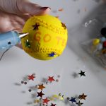 Adhering stars in different colors to a baseball to create an art piece