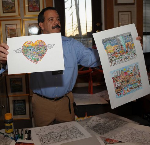 Image of a man named Jaime holding up posters of Charles Fazzino's paintings at ArtsFest
