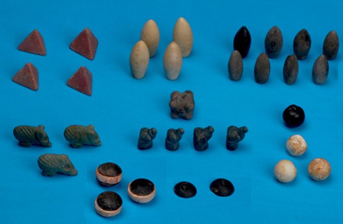 Lying on a board table are several different decorative rocks that are believed to be pieces to an ancient board game