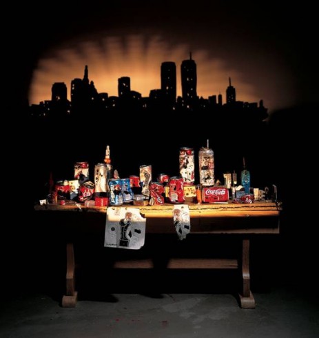 Image garbage arranged on a table so that it casts a shadow of a city skyline