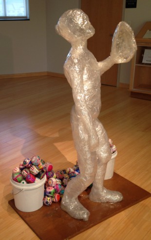 Image of a life size sculpture of a Little League player looking up into the sky, ready to catch a ball with his glove.