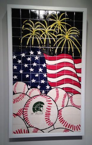 Image of artwork made from black tile with the American flag, yellow fireworks, and a pile of Little League baseballs.