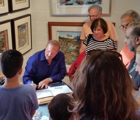 Charles Fazzino in his studio at Arts Fest drawing while fans look on