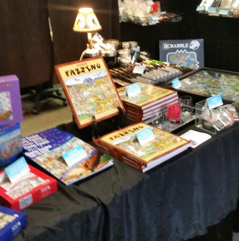 Stacks of Fazzino books, puzzles, gift cards and more on a table at Arts Fest