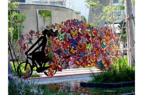 David Gerstein installation of a bicyclist with a colorful trail set in a park