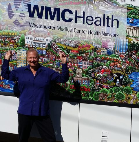 Charles Fazzino, in a blue button down, in front of the Westchester Medical Center Health Network Pop-Art bus