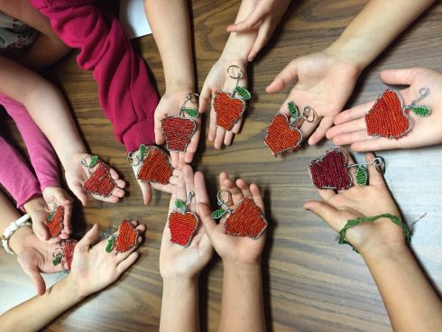 Childrens hands holding Fazzino inspired art project at the Kids Need More Art studio