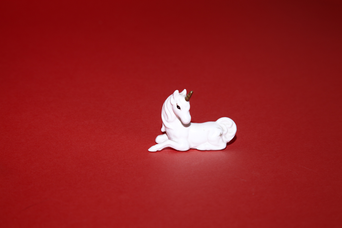 White unicorn shot on a red background shot by photographer Nicholas Rouke