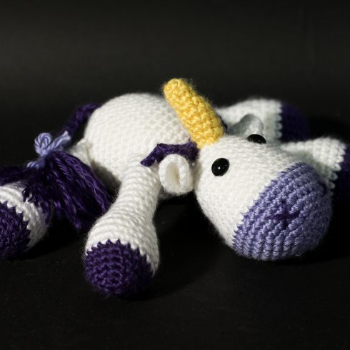 White and purple crocheted unicorn laying down | Christina's Crocheted Characters