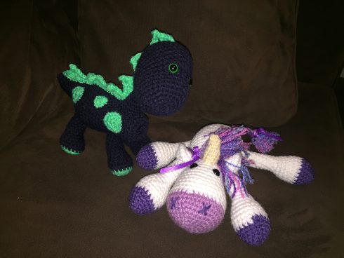 A navy and blue crocheted dinosaur standing next to a white and purple unicorn | Christina's Crocheted Characters