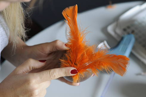 Applying orange feathers to a baseball