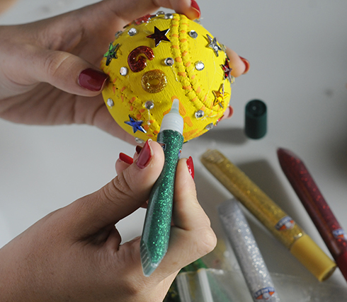 Using a glitter glue marker to write go team on a baseball