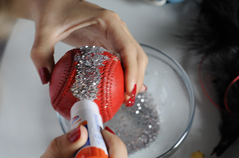 Adding glitter to a red baseball to create art