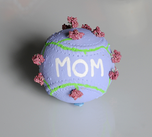 A purple painted baseball with Mom and flowers on it. 