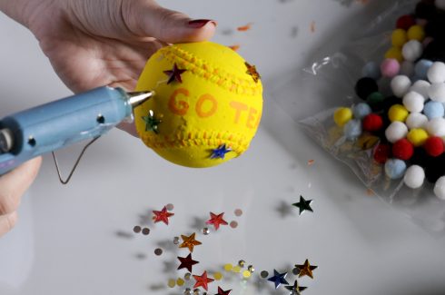 Adhering stars in different colors to a baseball to create an art piece