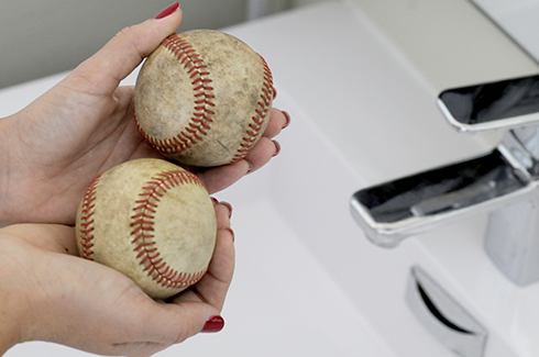 Holding two baseballs in preparation for cleaning them to create art