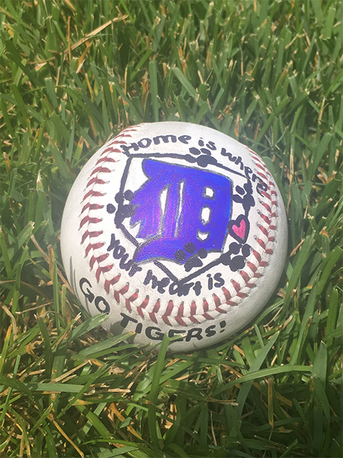 A baseball painted with a Detroit logo in purple