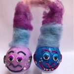 A pair of baseballs painted in blue and pink with giant fluffy hair to look like trolls