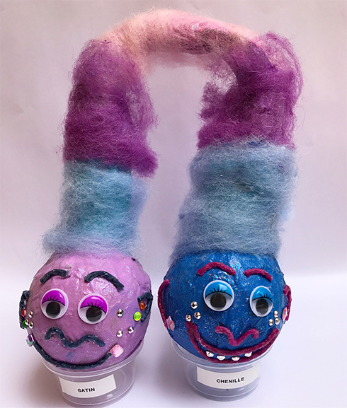 A pair of baseballs painted in blue and pink with giant fluffy hair to look like trolls