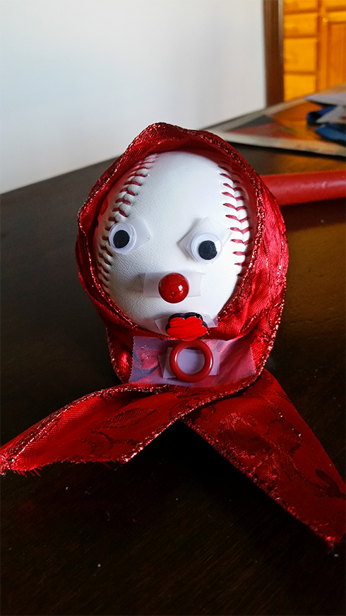 A baseball with a red cape over the head, googly eyes and a red nose looks like a grandma