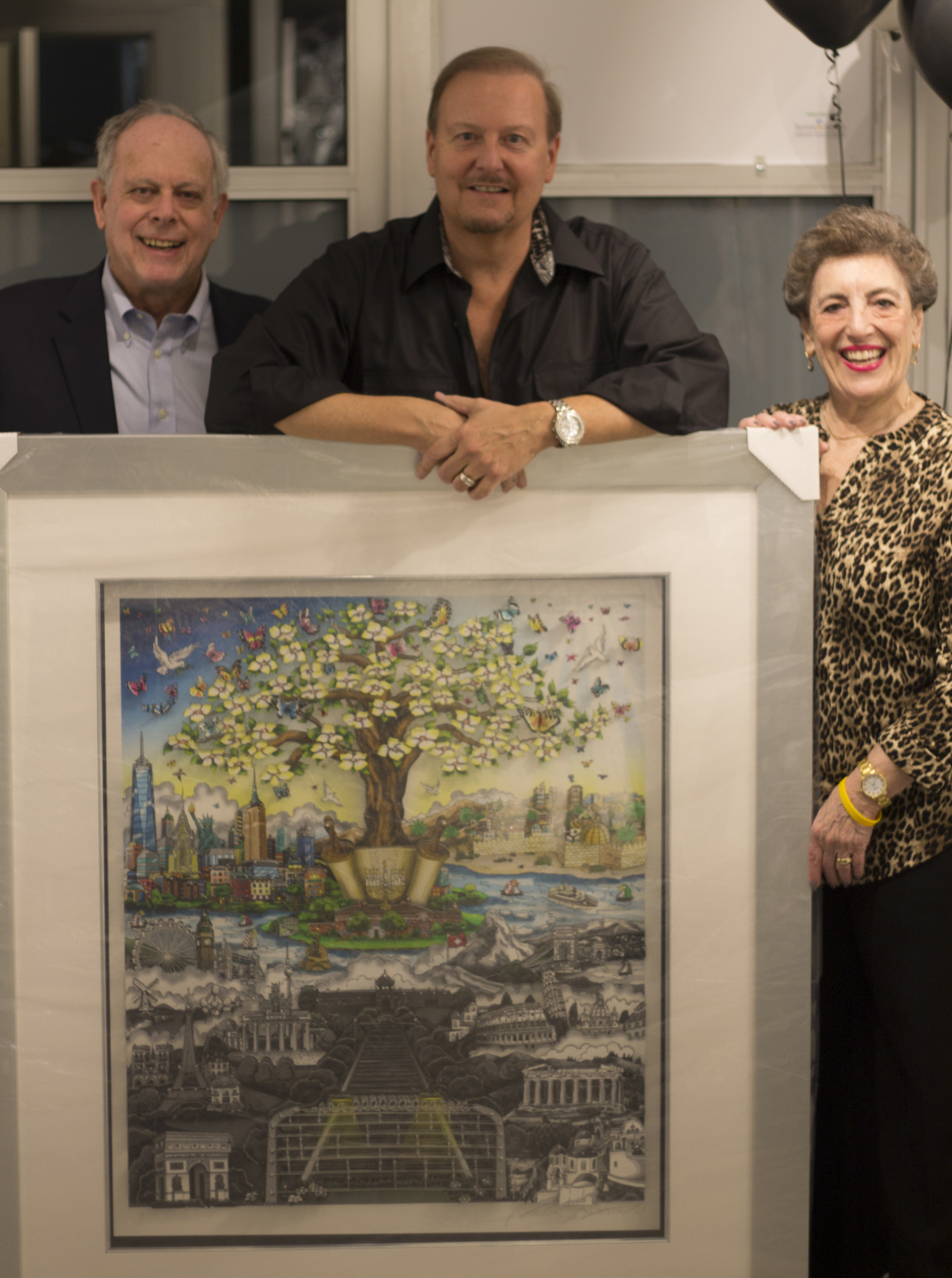 Charles Fazzino posing with a man and woman with the "After the Darkness" 3D Pop Art piece