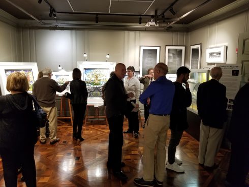 People gathered in a dim lit gallery at the Holocaust Memorial & Tolerance Center of Nassau County (HMTC) for Charles Fazzino's exhibit 