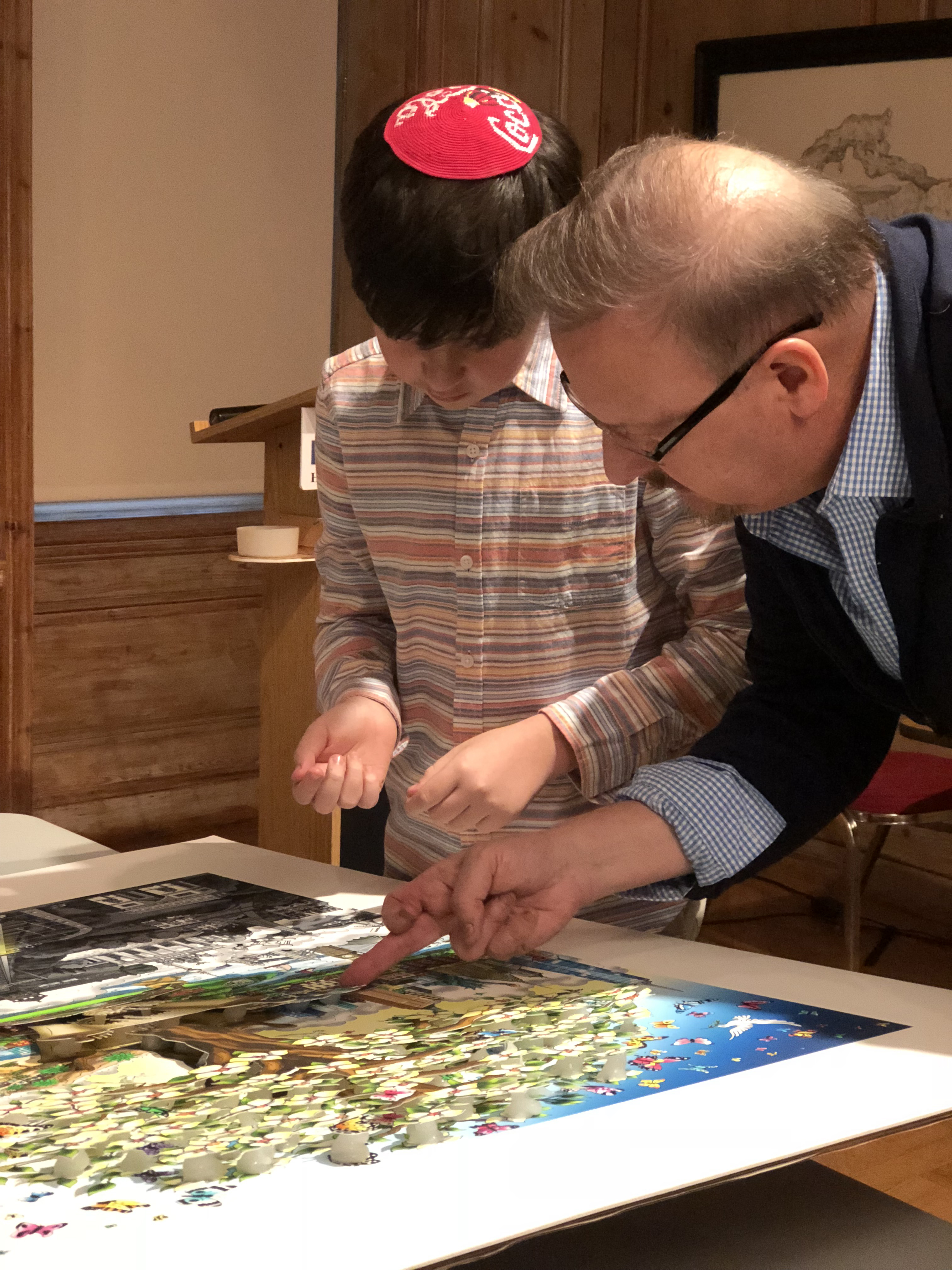 Young brown haired boy wearing an stripped shirt watching Charles Fazzino create 3d artwork