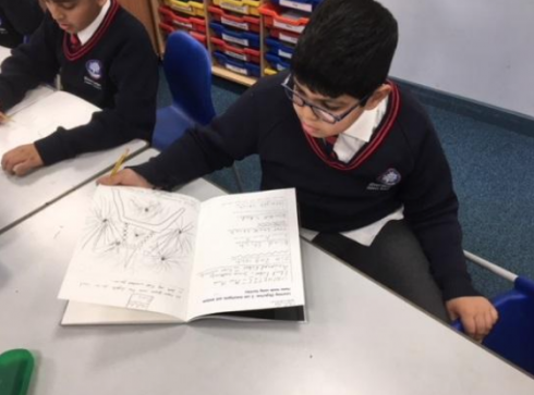 Little brown haired boy with glasses drawing fireworks in his notebook