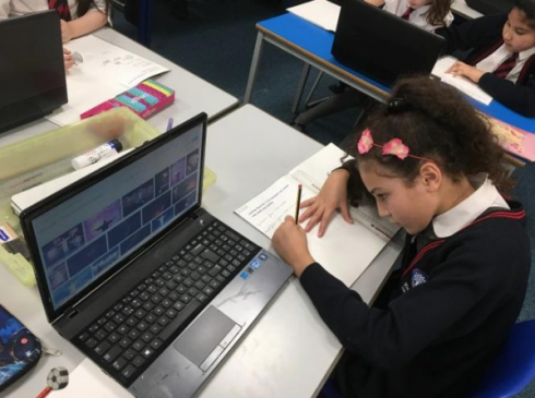 Little girl in a pink headband doing New Years Celebration research on her laptop