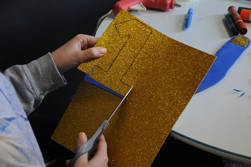 Cutting out the number 1 in gold sparkle for foam finger