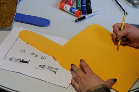 Drawing the fingers on a orange piece of foam shaped like a hand