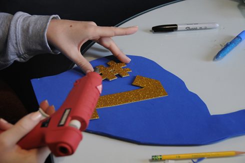 Gluing down a gold sparkly #1 on a foam finger