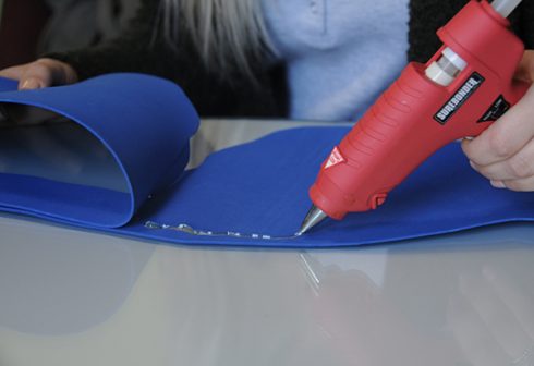 Gluing two pieces of blue foam together with a glue gun