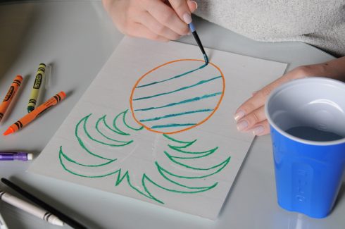 Painting the fruit part of a pineapple with blue watercolor