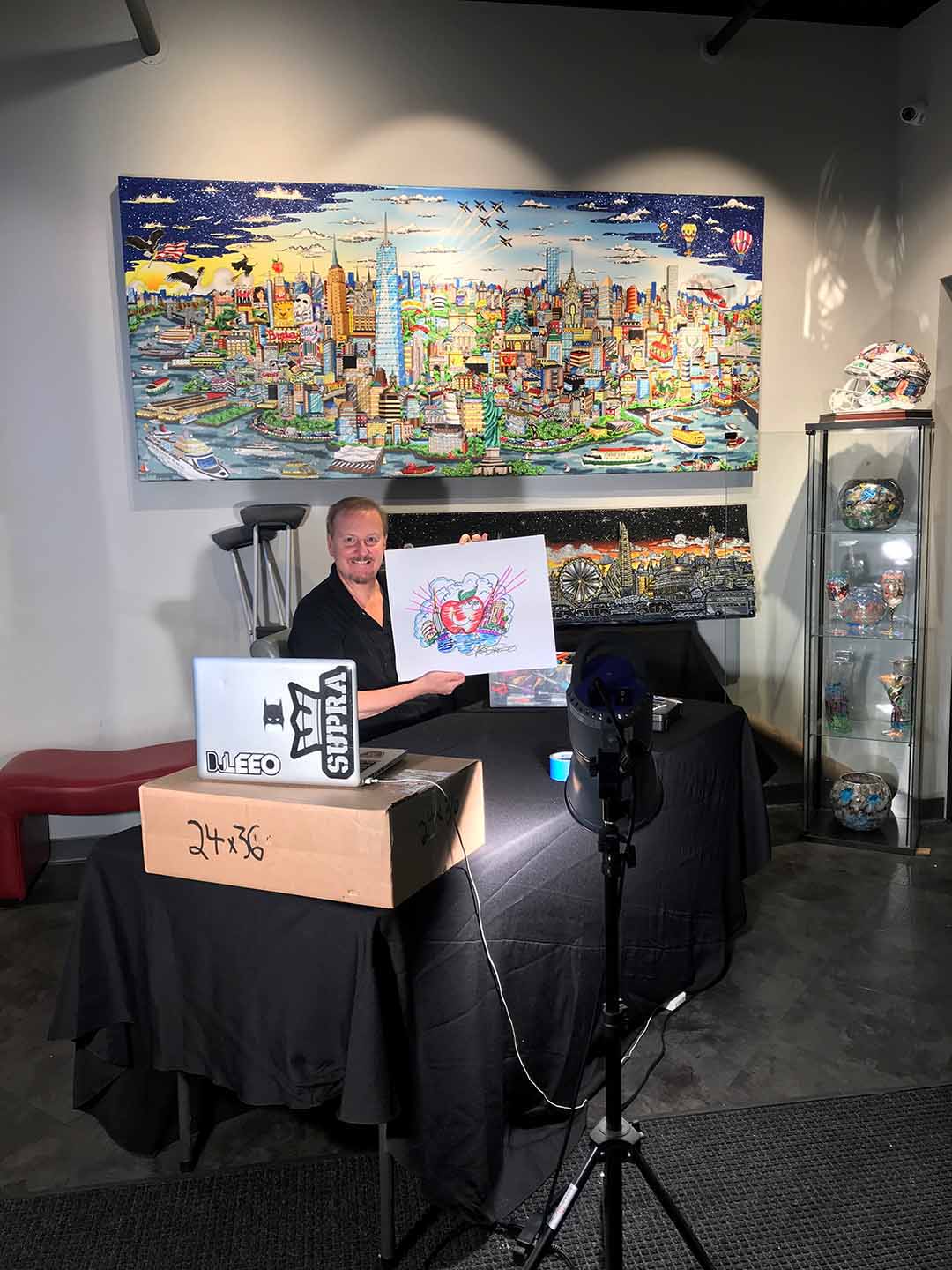 Charles Fazzino holding up a pop art doodle during his skype interview in his gallery. 