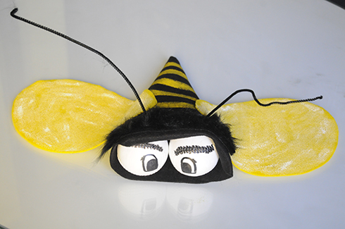 A bee made out of black and yellow felt with two baseball for the eyes