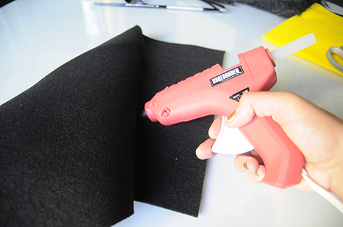 Using a gun to glue two pieces of felt together for the bee body