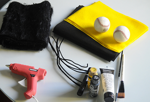 Supplies on a table including yellow and black felt, glue gun, paint, brushes for making a bee