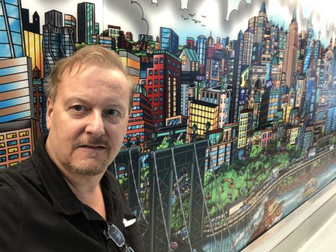 Charles Fazzino taking a selfie in front of his New York City Mural in NYU Langone Health