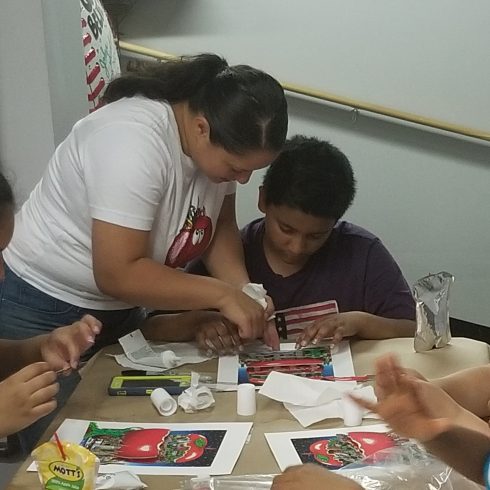 A female educator from "It Takes a Village to Educate a Child" helping a student create their very own Fazzino 3D Pop Art piece 