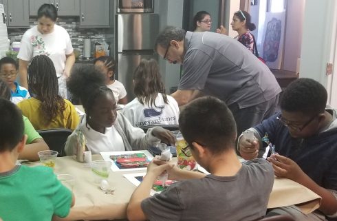 An overview of children sitting at two tables working on their 3D pop artwork at Charles Fazzino studios in New Rochelle