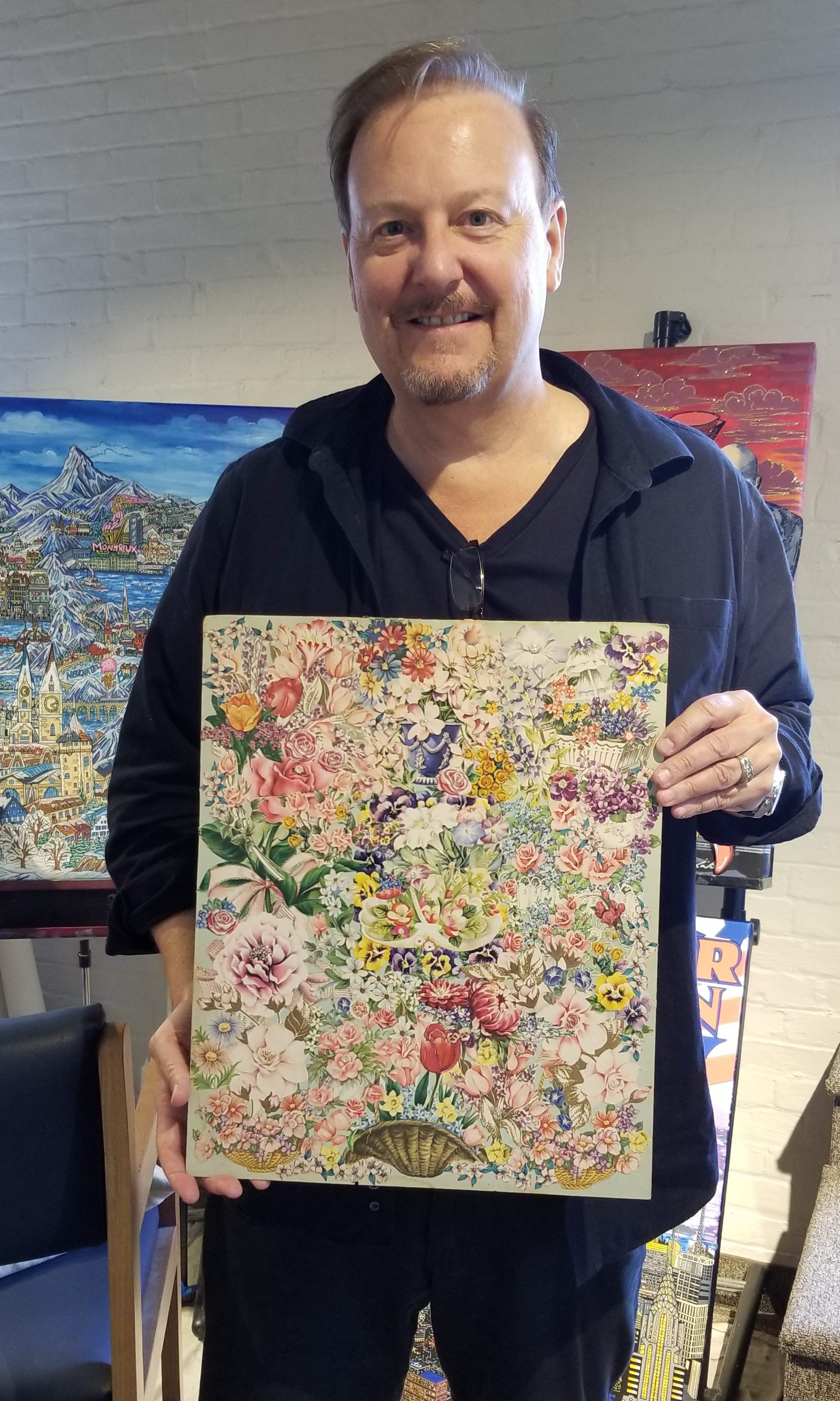 Charles Fazzino standing up holding a multi-colored floral art piece