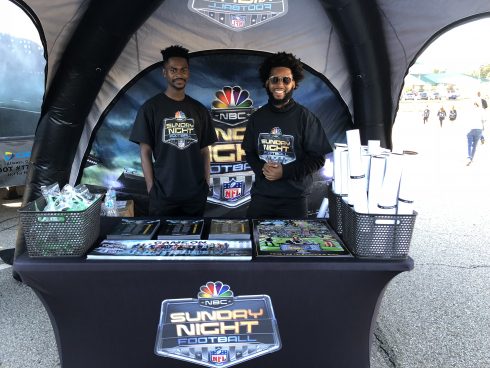 Hanging out at the Sunday Night Football booth with art posters by Fazzino and brochures and giveaways