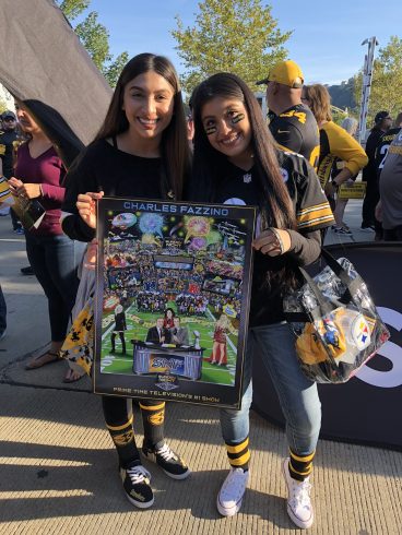 Two Sunday Night Football fans dressed in uniforms holding a Fazzino poster are all smiles at the event