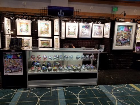 The Fazzino Super Bowl booth featuring framed artwork, mini football helmets and poster art