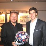 Eli Manning accepts a hand-painted helmet from Eli Manning at The Taste of the NY Giants charity event