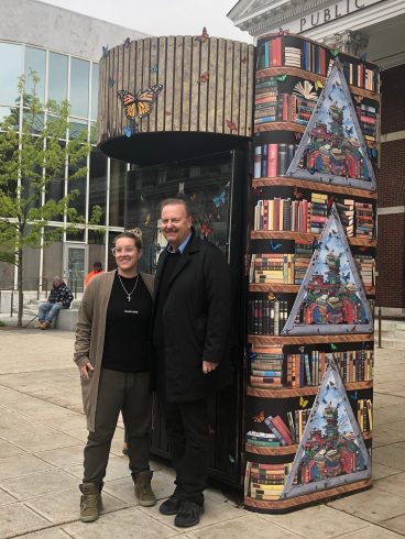 Charles and Heather Fazzino in front of a kiosk painted with books & butterflies.