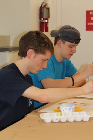 Andrew working on a painting alongside another boy.