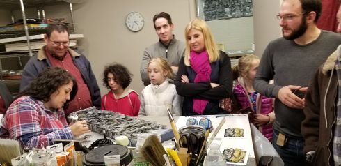 A crowd of people observing Fazzino's work on a table during ArtsFest.